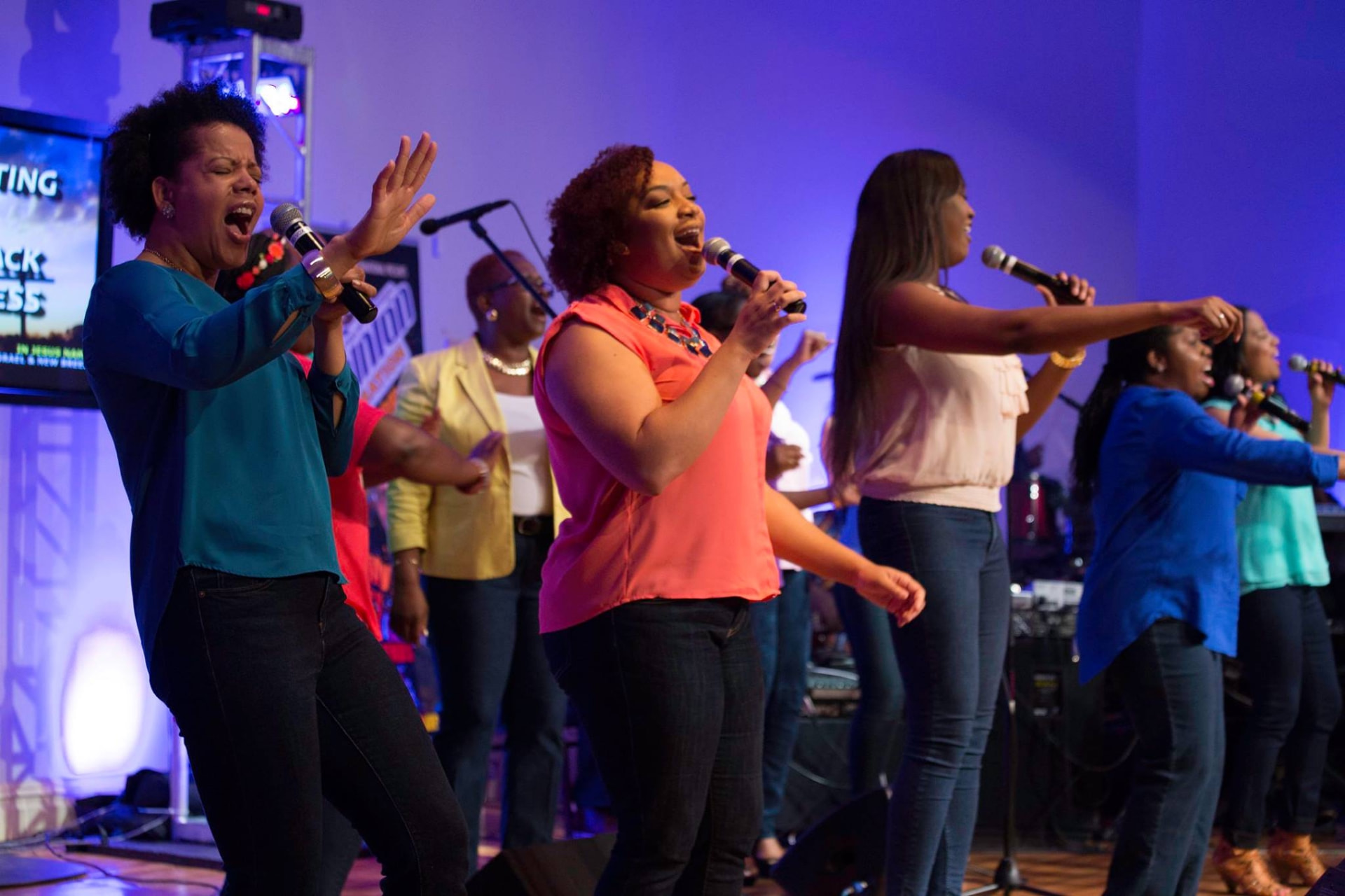 Praise team singing under stage lights
